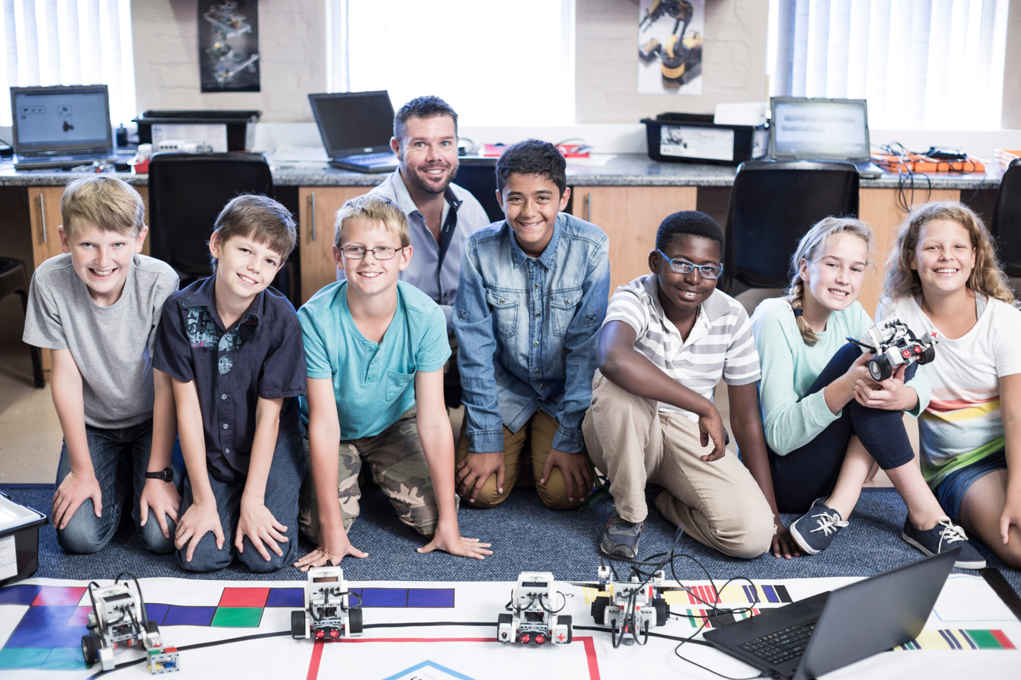 Portrait of smiling kids with teacher in robotics class