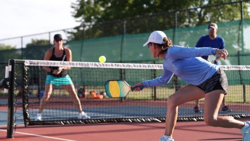 A woman hits a dink shot while playing pickleball.