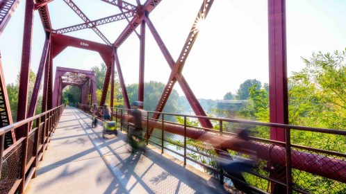 Motion blur bikers cross a bridge over the Boise River