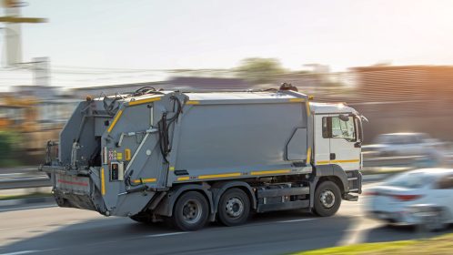 Recycling gray garbage truck driving on highway with motion blur speed effect.