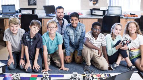 Portrait of smiling kids with teacher in robotics class